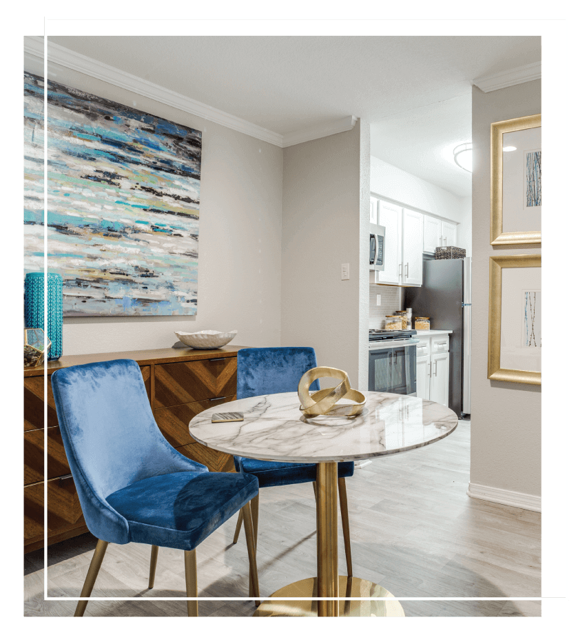 designer chair next to a small, round, marble table with brass base and kitchen in the background.