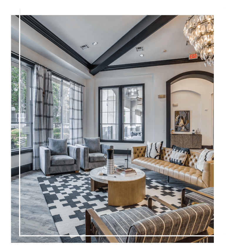 Luxurious lobby with large windows, ample natural light, vaulted ceilings with crown molding, chandelier, and designer furniture.