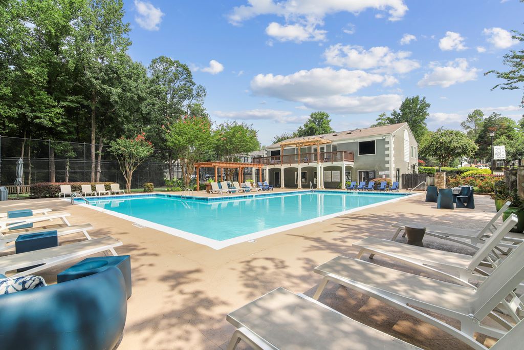 Elliot Norcross swimming pool with sundeck and lounge chairs surrounded by native landscaping with leasing office in background.