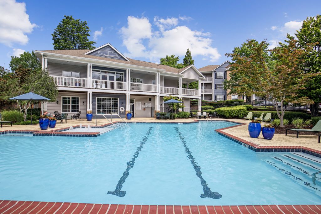 Halston Shiloh Valley swimming pool with sundeck and seating with leasing office and apartment buildings in background surrounded by native landscaping.