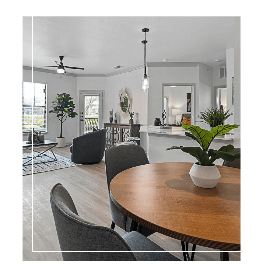 open style floor plan in apartment with dining table in foreground and kitchen and living room in background with plenty of natural lighting through windows