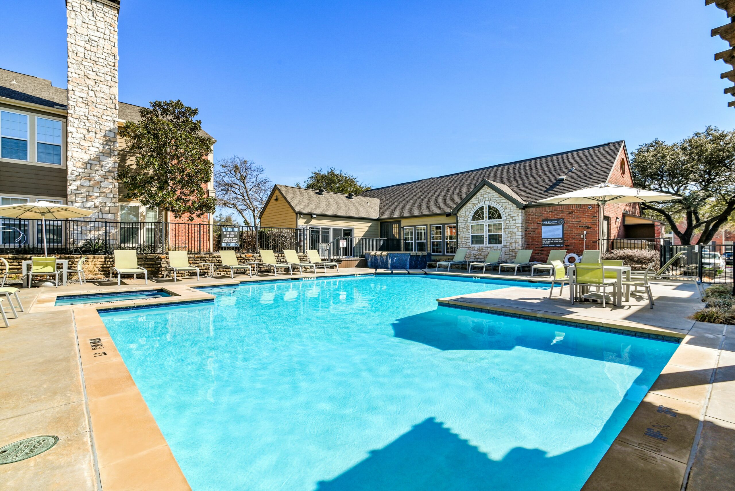 Preserve at Preston swimming pool with sundeck and lounge chairs surrounded by native landscaping with leasing office in background.