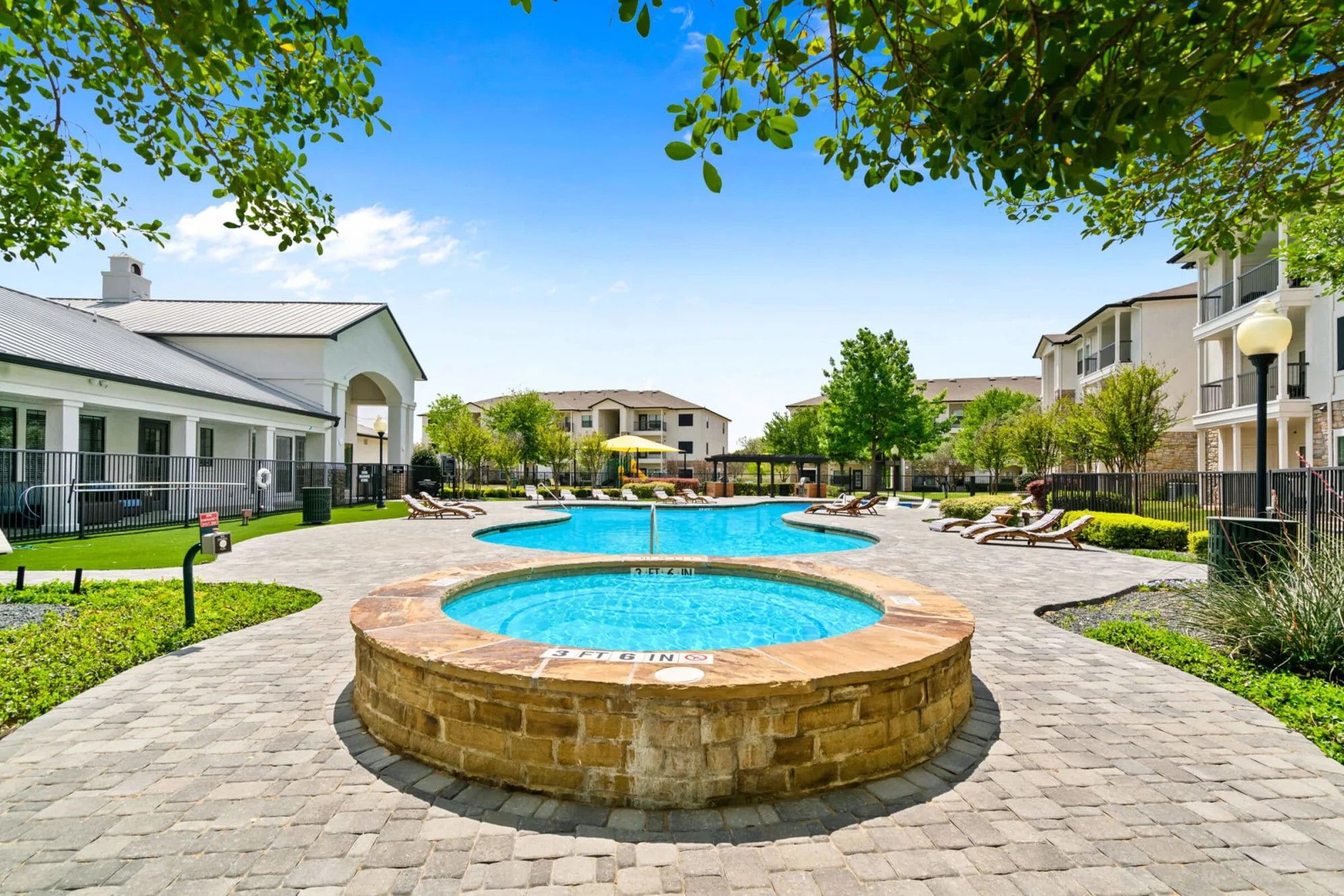 View of the spa and pool next to the clubhouse. Landscaped surroundings.