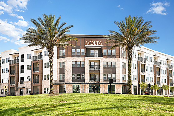 Front of apartment building with palm trees on both sides.